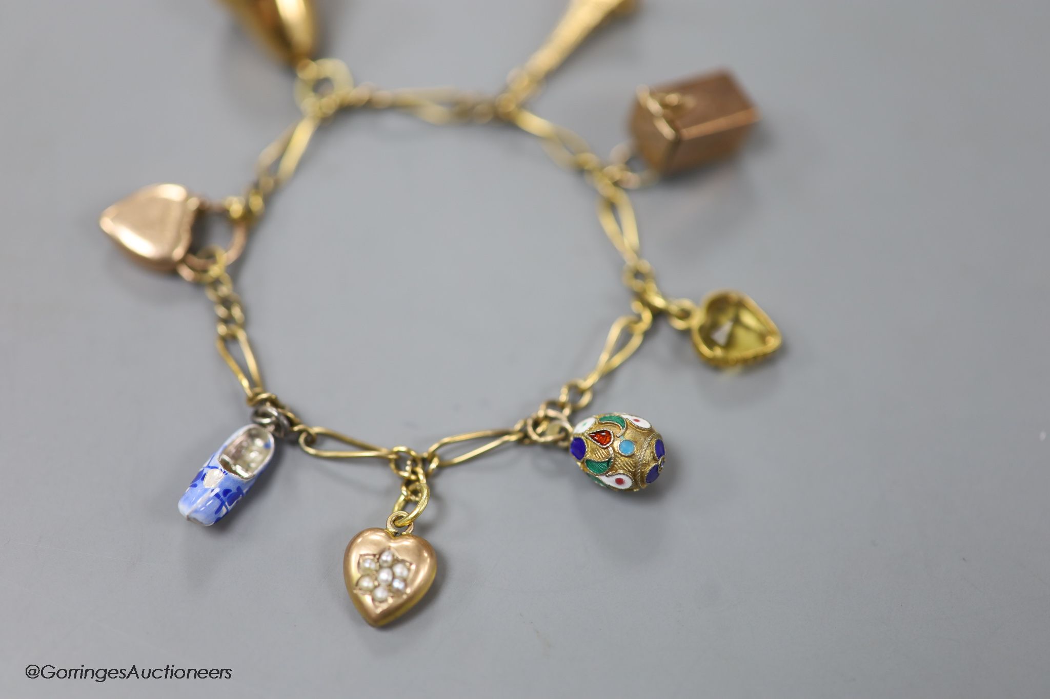 A small Edwardian 9ct gold charm bracelet, hung with eight assorted charms, approx. 16cm, gross weight 9.7 grams.